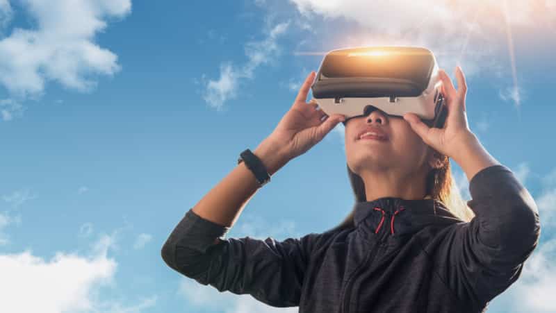 Femme portant casque de réalité virtuelle au soleil